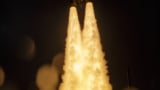 Burning trails beneath the James Webb Space Telescope as it launches