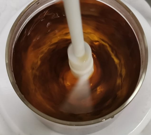 Einstein's tea leaf paradox Photo showing a white plastic stirrer agitating amber-brown liquid in a metal container